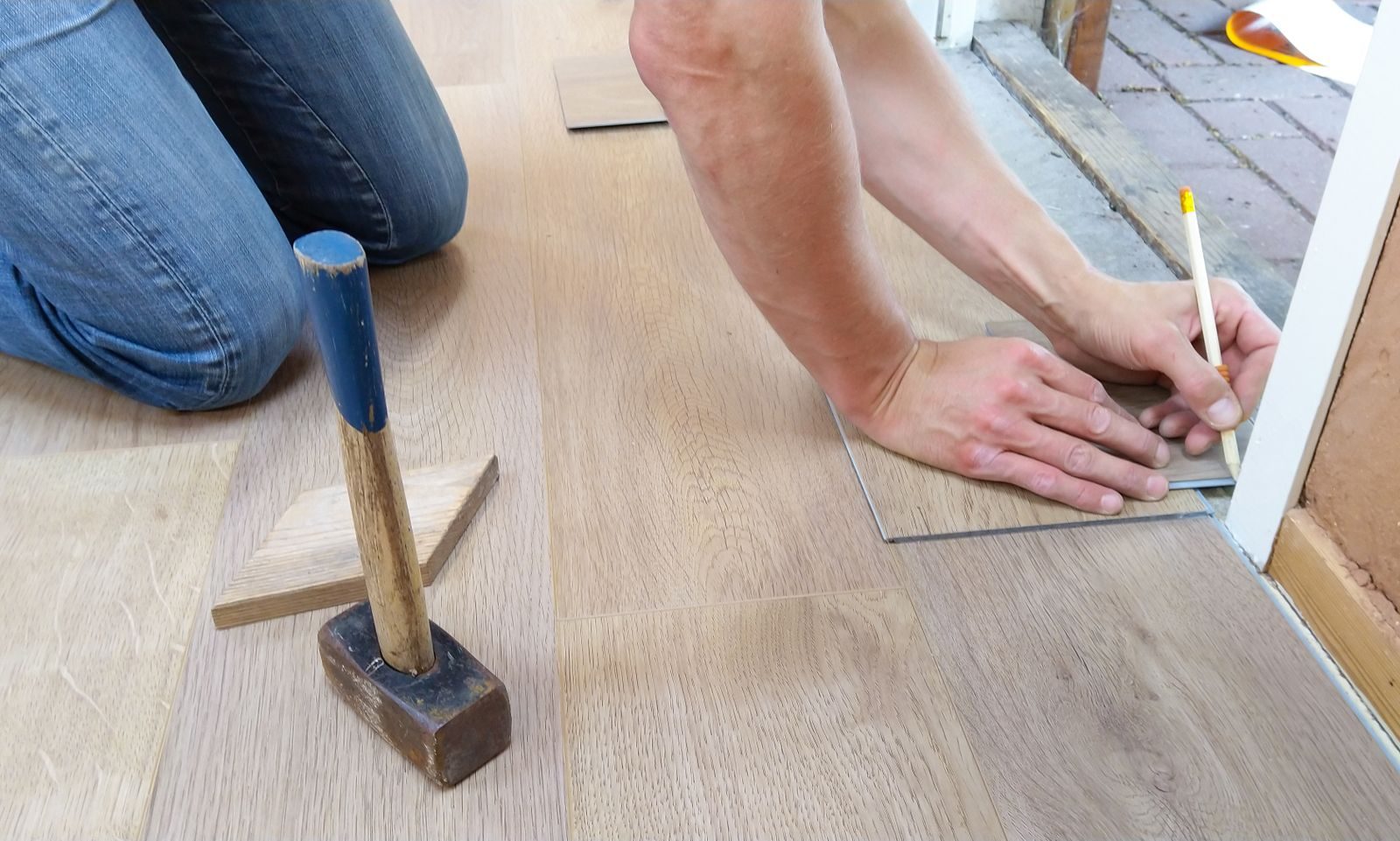 A Balmoral Neighborhood home services craftsman carefully measures and marks Luxury Vinyl Plank Flooring for precise installation.