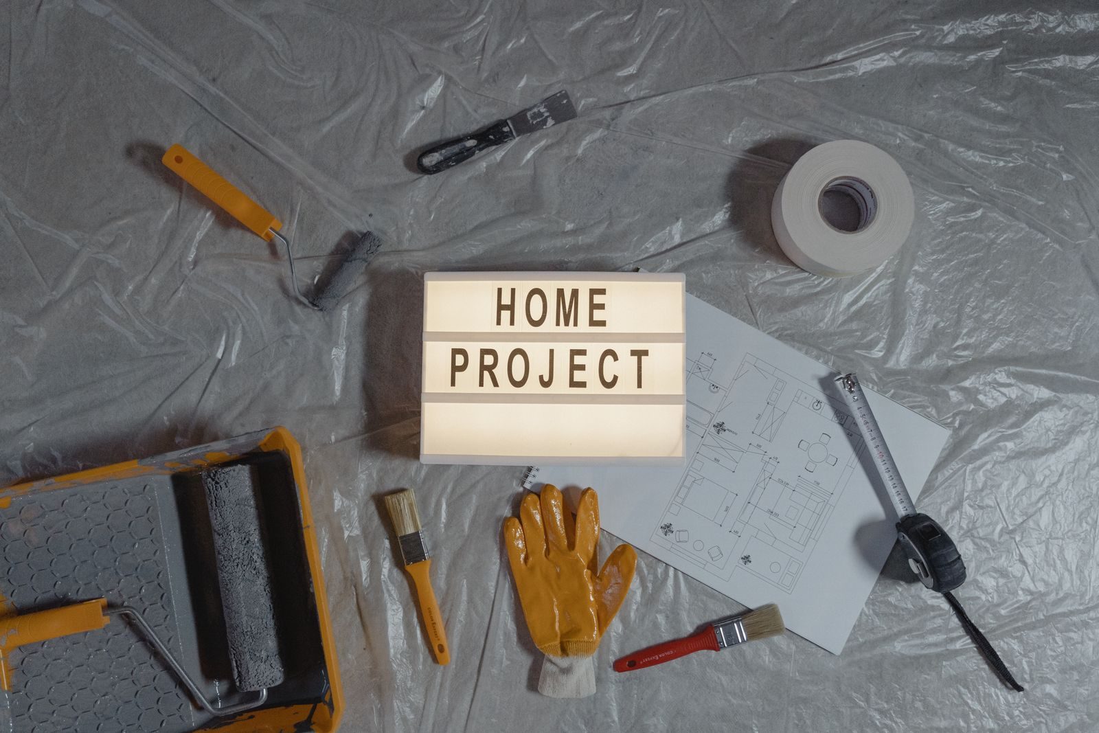 Bluebird Estates Neighborhood home services Flat lay of home improvement setup with tools, gloves, and floor plan for DIY projects.